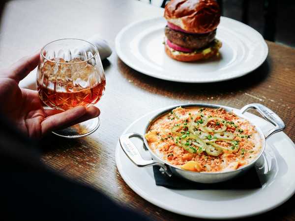 Glass of cognac and cheesy baked pasta